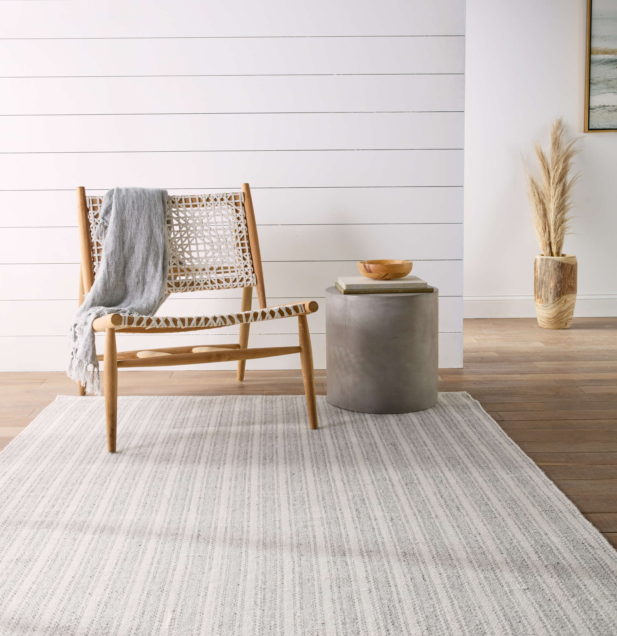 Gray and white striped indoor/outdoor rug under a wooden chair and side table