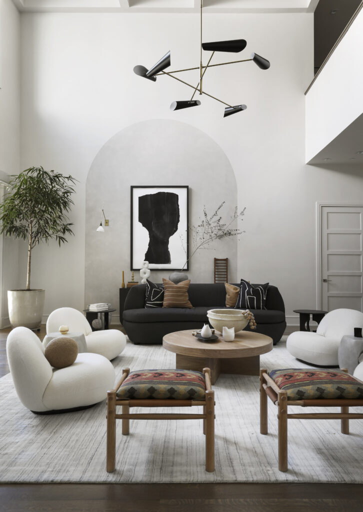 A tan rug in a living room with white furnishings and black and white art