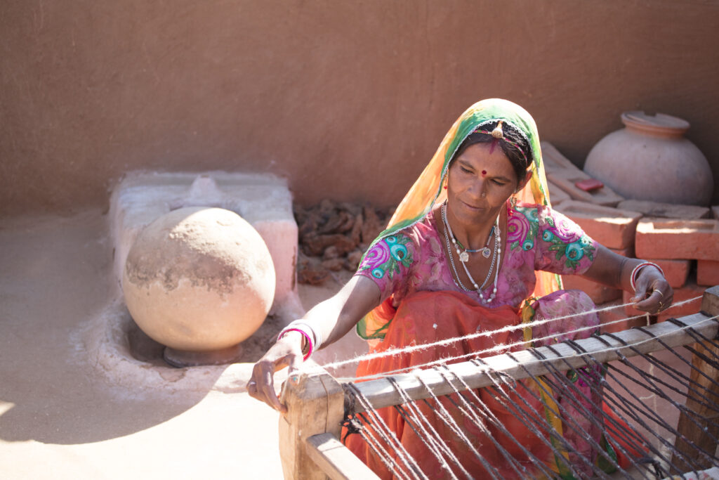 A woman in a colorful sari sits at a loom