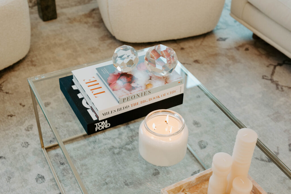 An acrylic coffee table is styled with books and candles