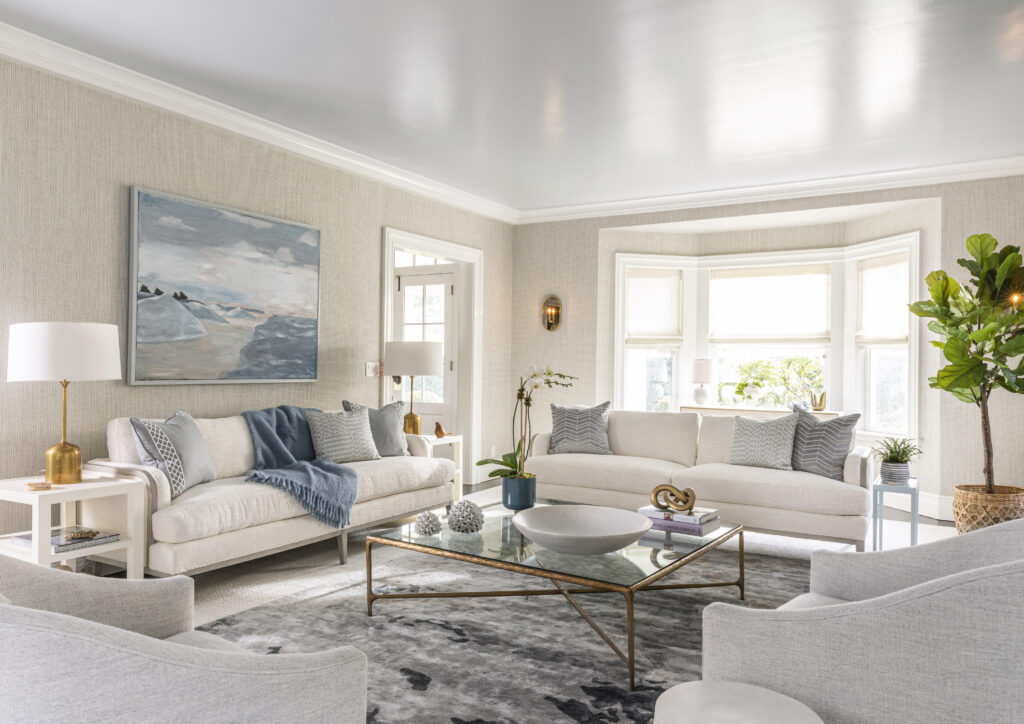 A cream colored living room with white couches and blue accents