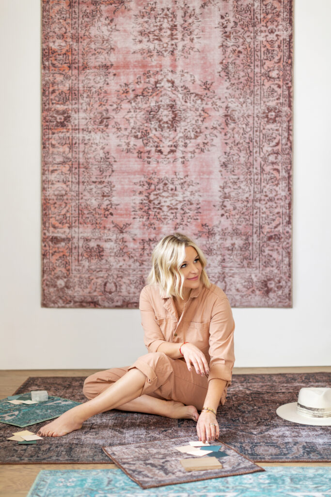 Kate Lester sits among a pile of rugs