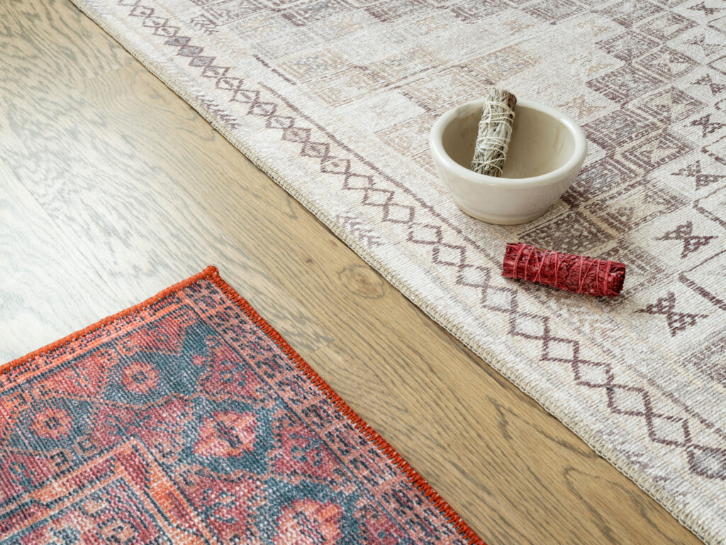 A blue and red rug and a tan colored rug with sage bundles