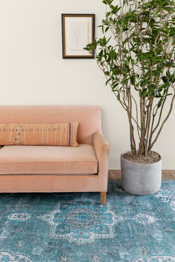 A light pink sofa on top of a blue patterned rug