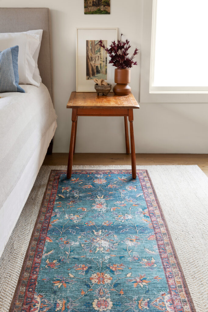A bedroom with a blue runner on top of a natural rug