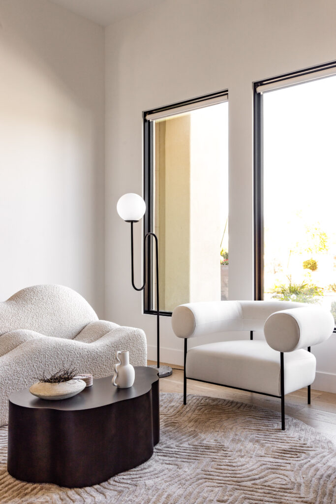 A white-toned sitting area with sculptural white chairs and a light gray textured rug