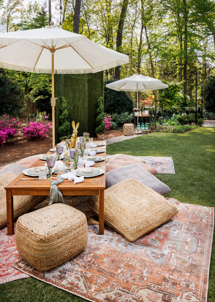 An outdoor setting with pattern outdoor rugs, poufs, low tables, and umbrellas