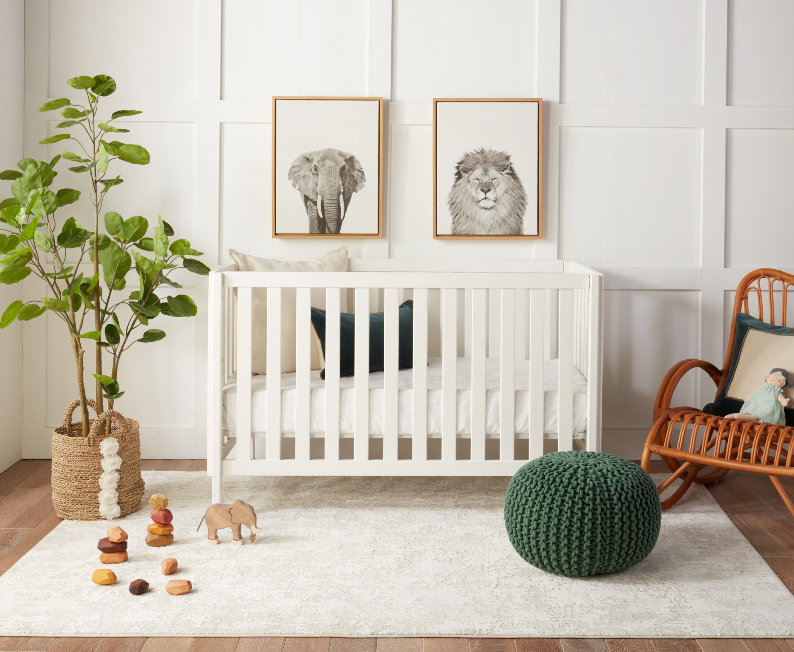 An all white nursery with a green pouf and animal prints