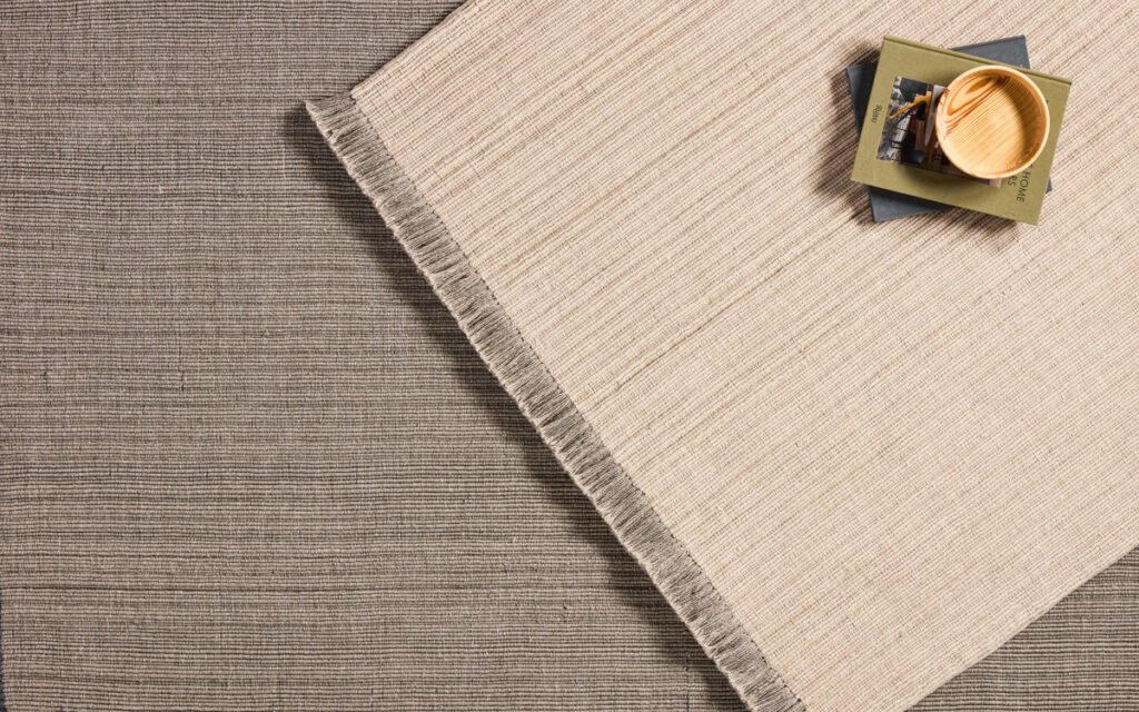 Two indoor/outdoor rugs in neutral tan colorways are layered on top of each other