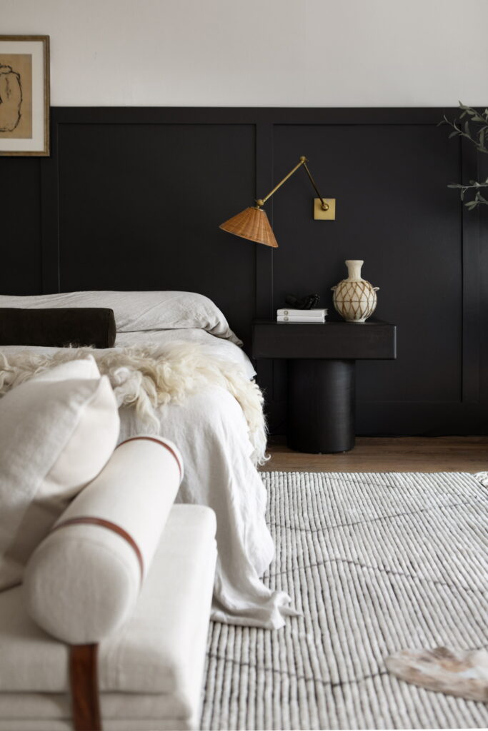 A white bed and soft in a bedroom with leather accents and dark wall