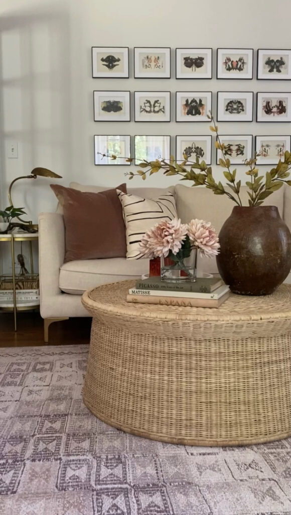 A living room with gallery wall, beige couch, round coffee table, and neutral patterned rug