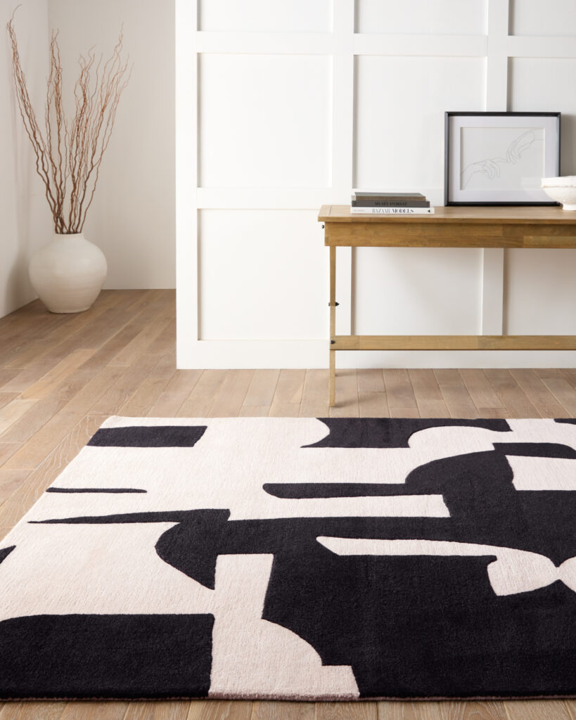 A black-and-white graphic rug with a wooden console behind