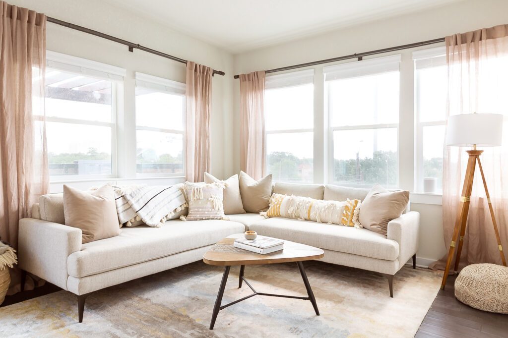 A white section sofa is covered with neutral colored throw pillows