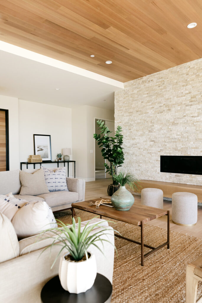 A living room with natural rug, stone wall cream furnishings and wooden accents
