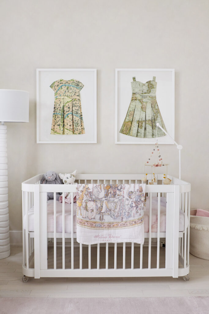 A nursery with white crib, rug, dress artwork, and standing lamp